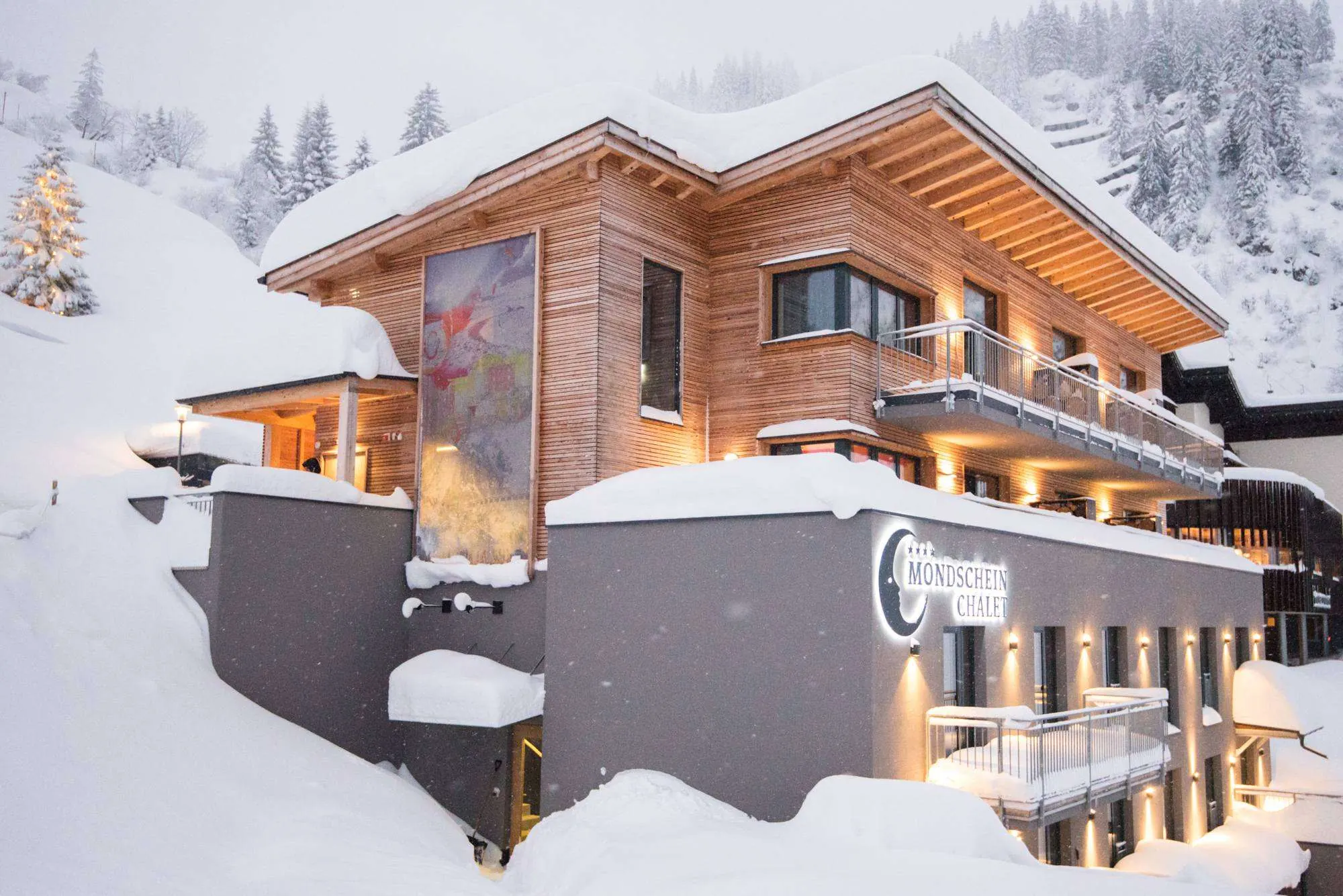 Das Mondschein Chalet im Schneefall, in der Dämmerung beleuchtet