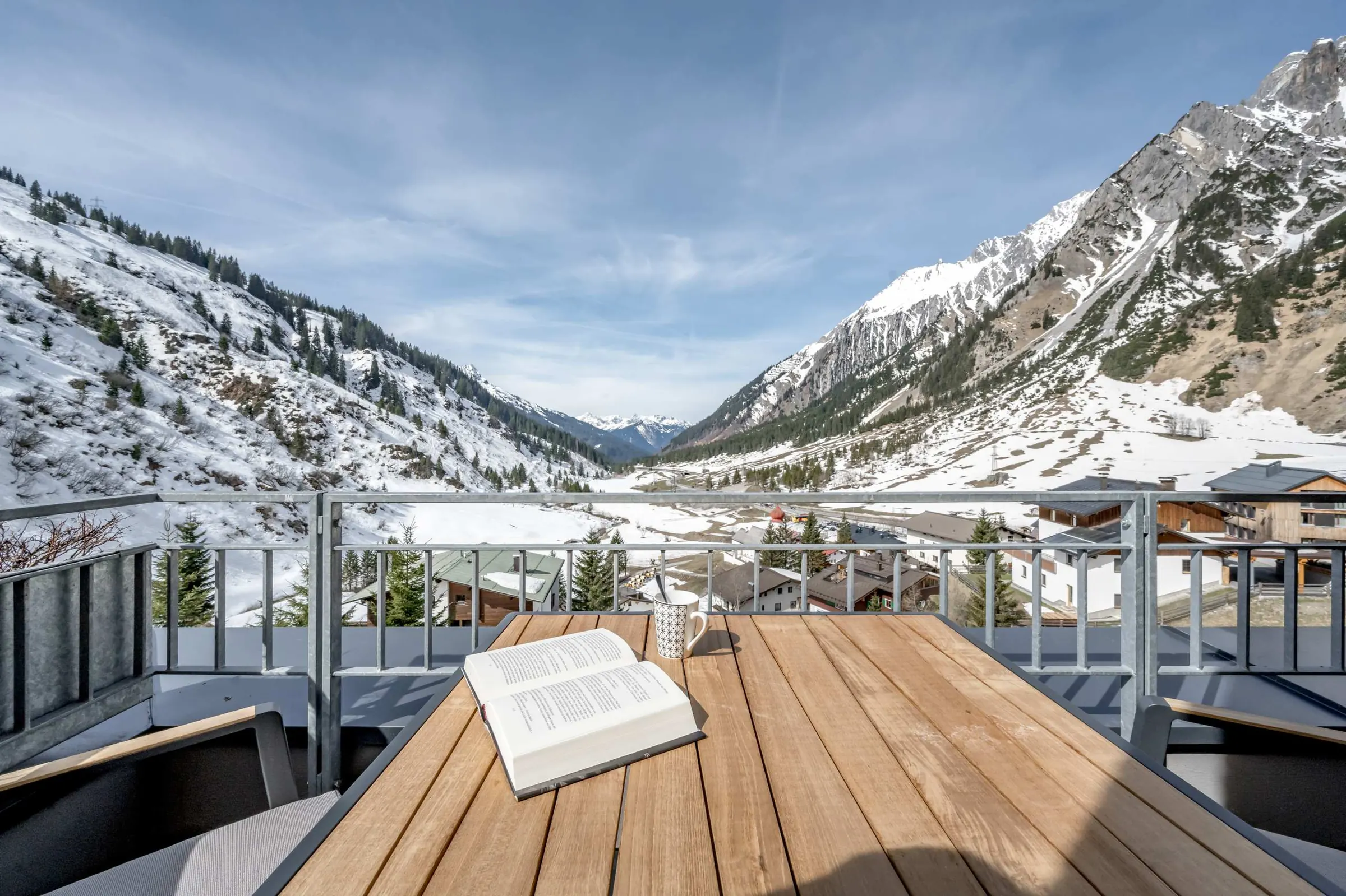 Balcony table with a book and a view of the snowy valley