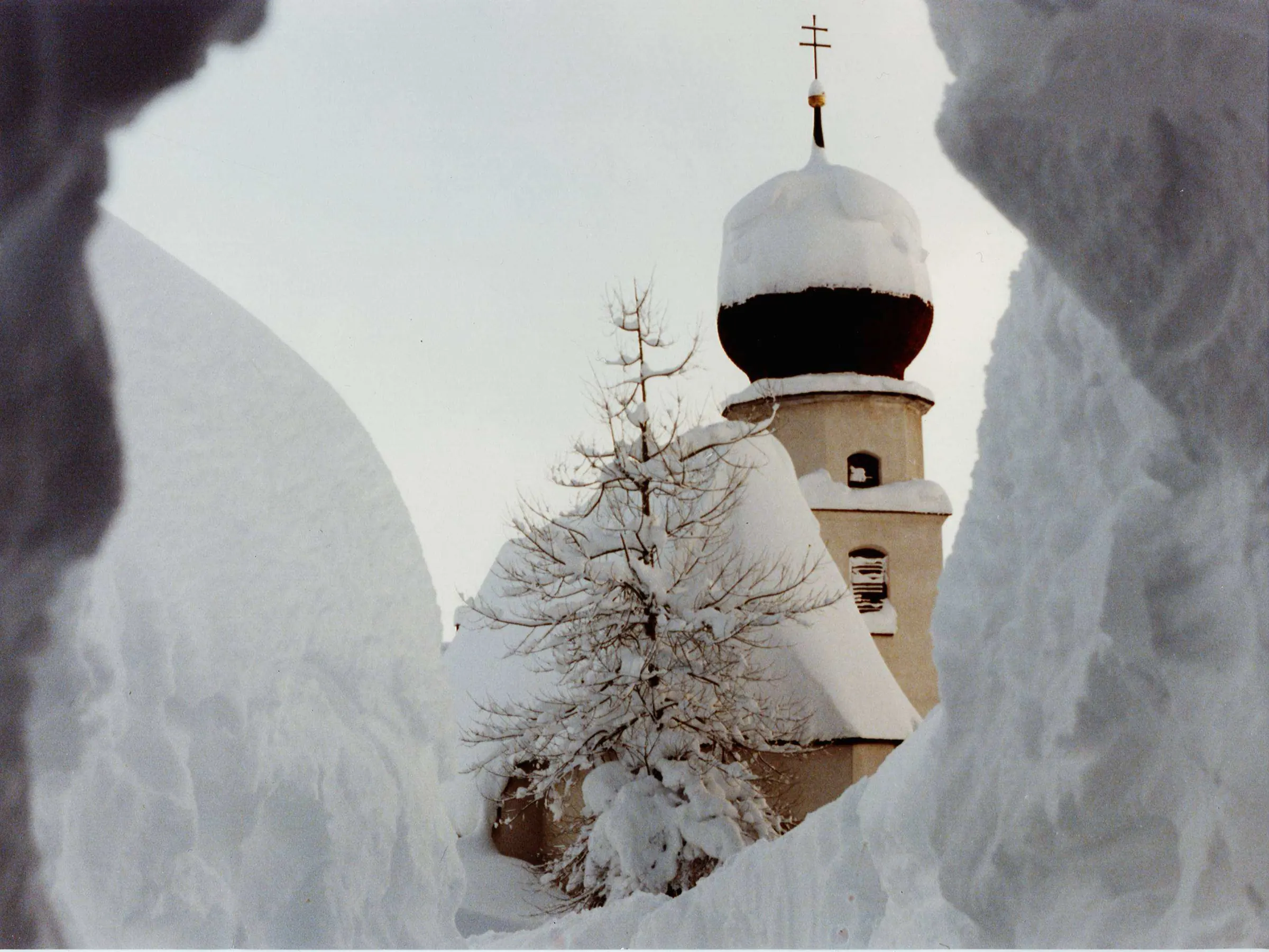 Church tower with an onion dome between high walls of snow
