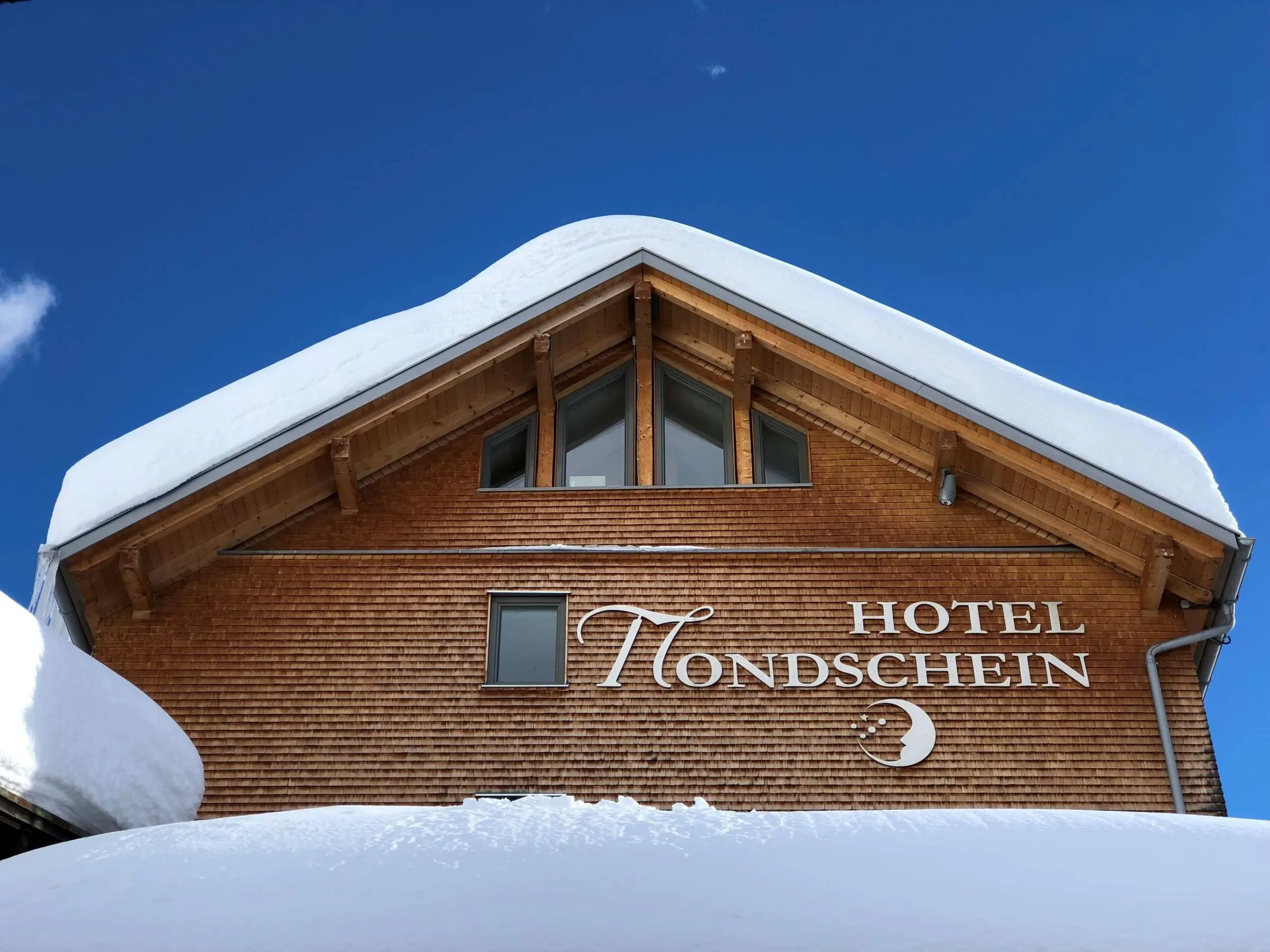 Giebel mit dem Schriftzug Hotel Mondschein unter einer dicken Schneedecke