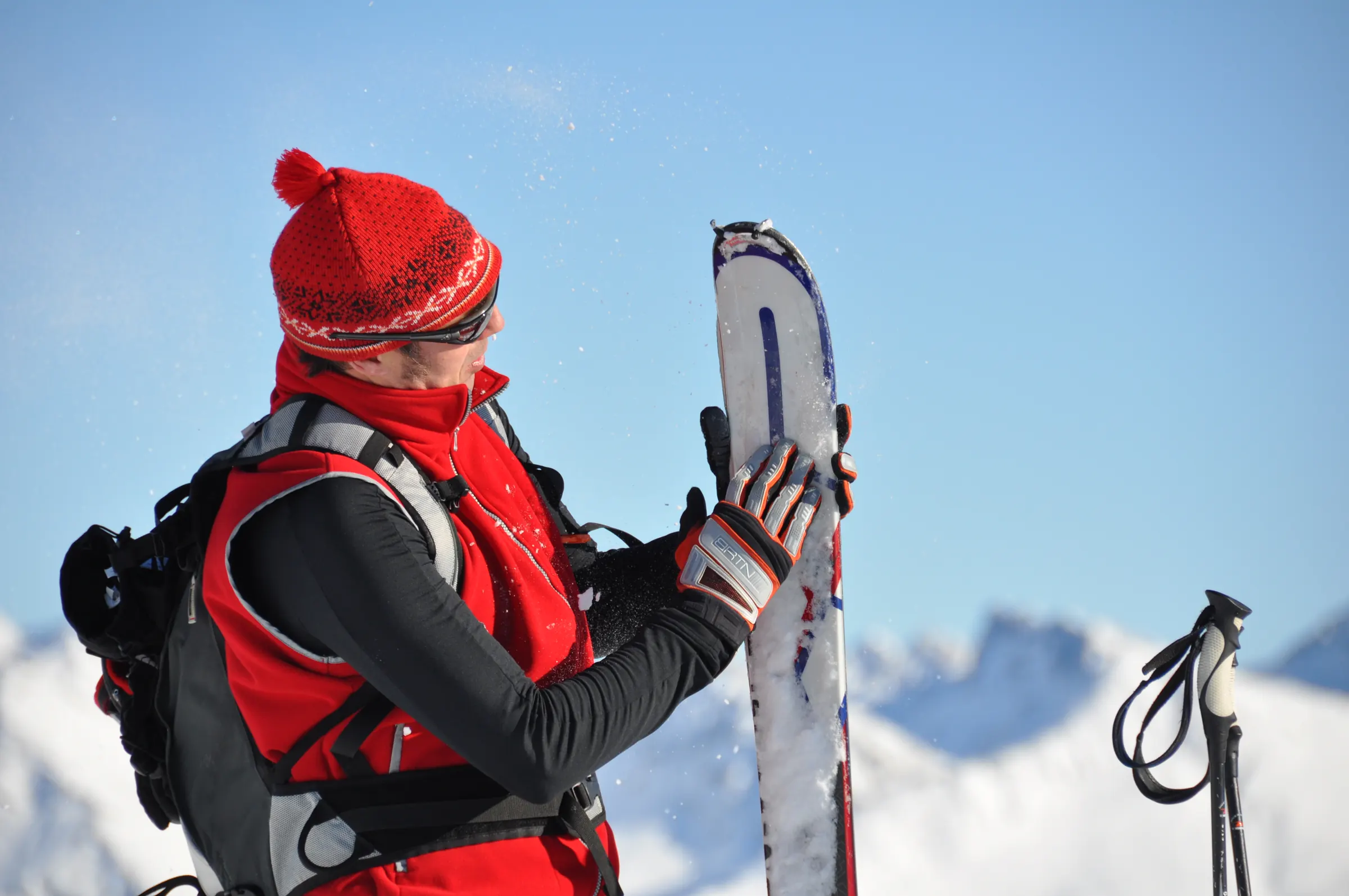 Skiër met rode muts en ski's in de hand
