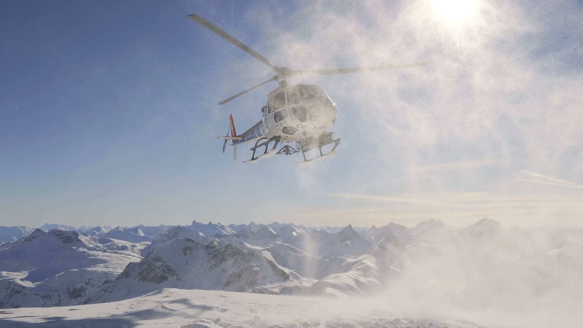 Helikopter boven besneeuwde toppen bij het heliskiën