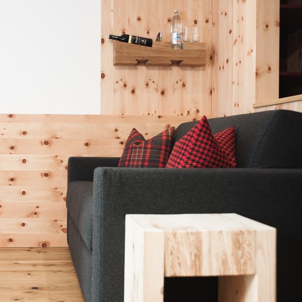 Cozy pinewood interior with dark grey sofa and electric-free minibar shelf in the rooms at Ski-Hotel Mondschein in Stuben am Arlberg