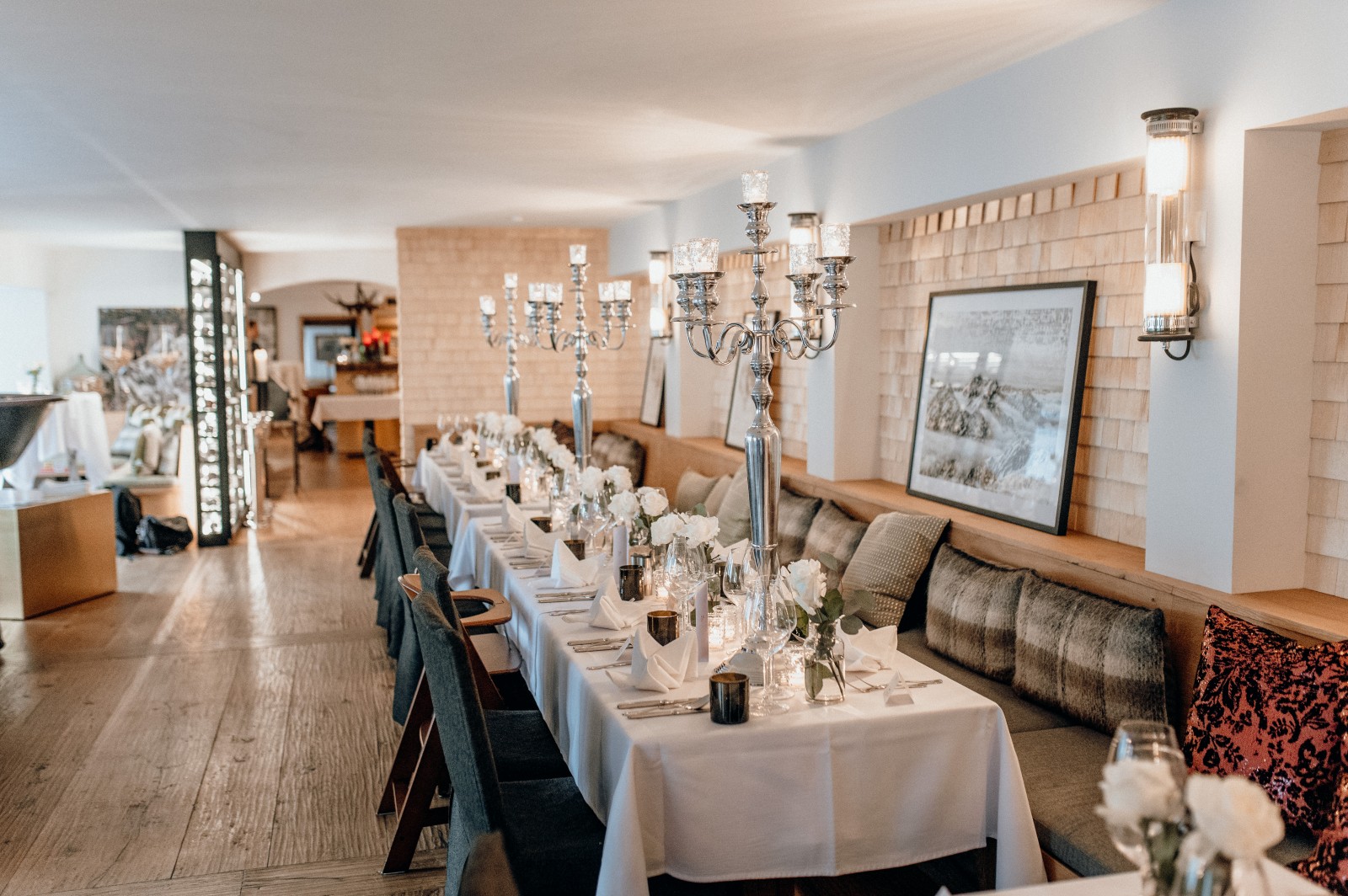 Long table set with white roses, candles, and silver candelabras for a wedding celebration at Panorama Restaurant in Ski-Hotel Mondschein, Stuben am Arlberg