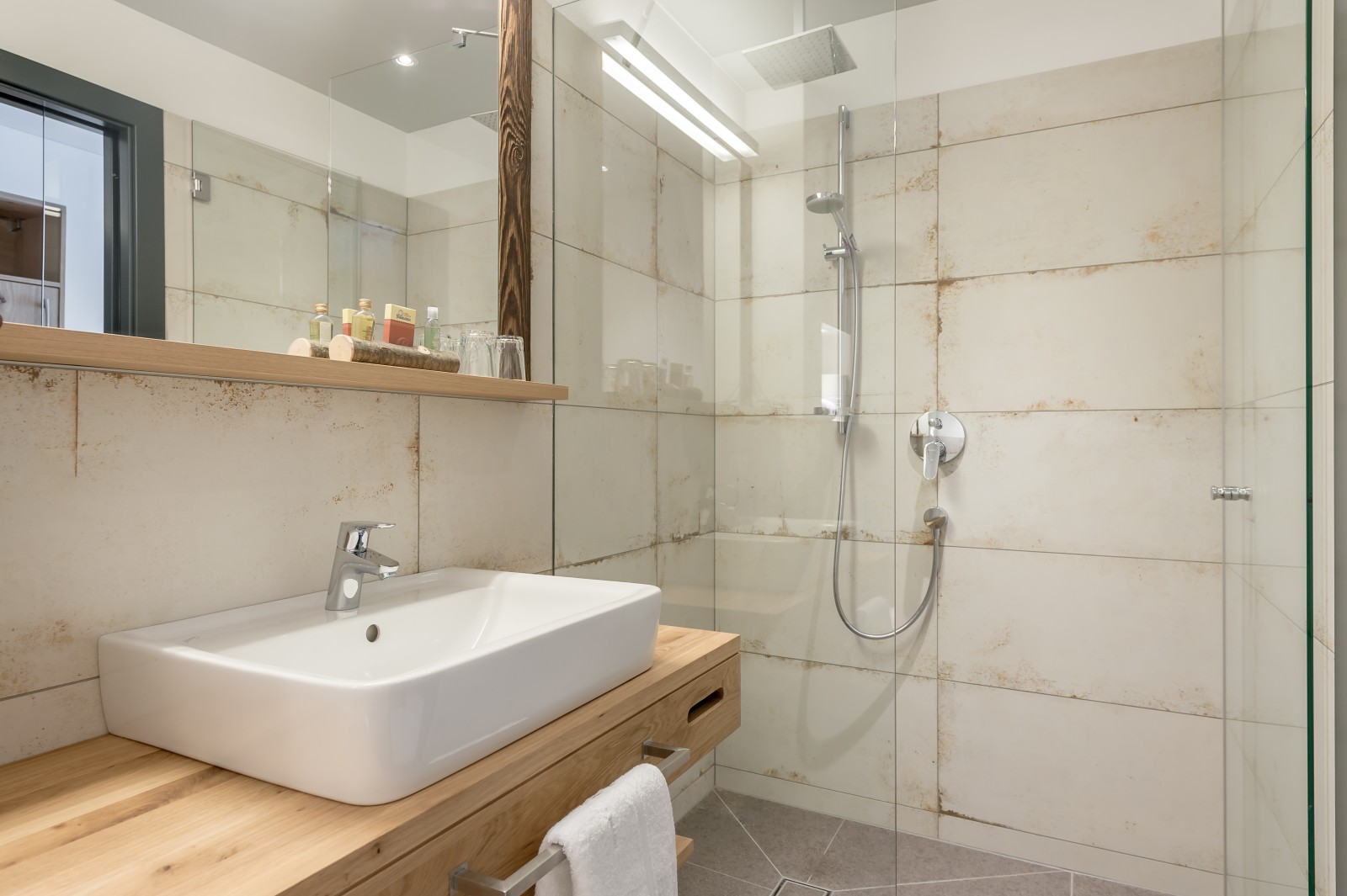 Modern bathroom in the Private Double at Chalet Mondschein in Stuben am Arlberg, Austria – with walk-in rain shower, natural stone tiles, wooden vanity, and eco-friendly amenities