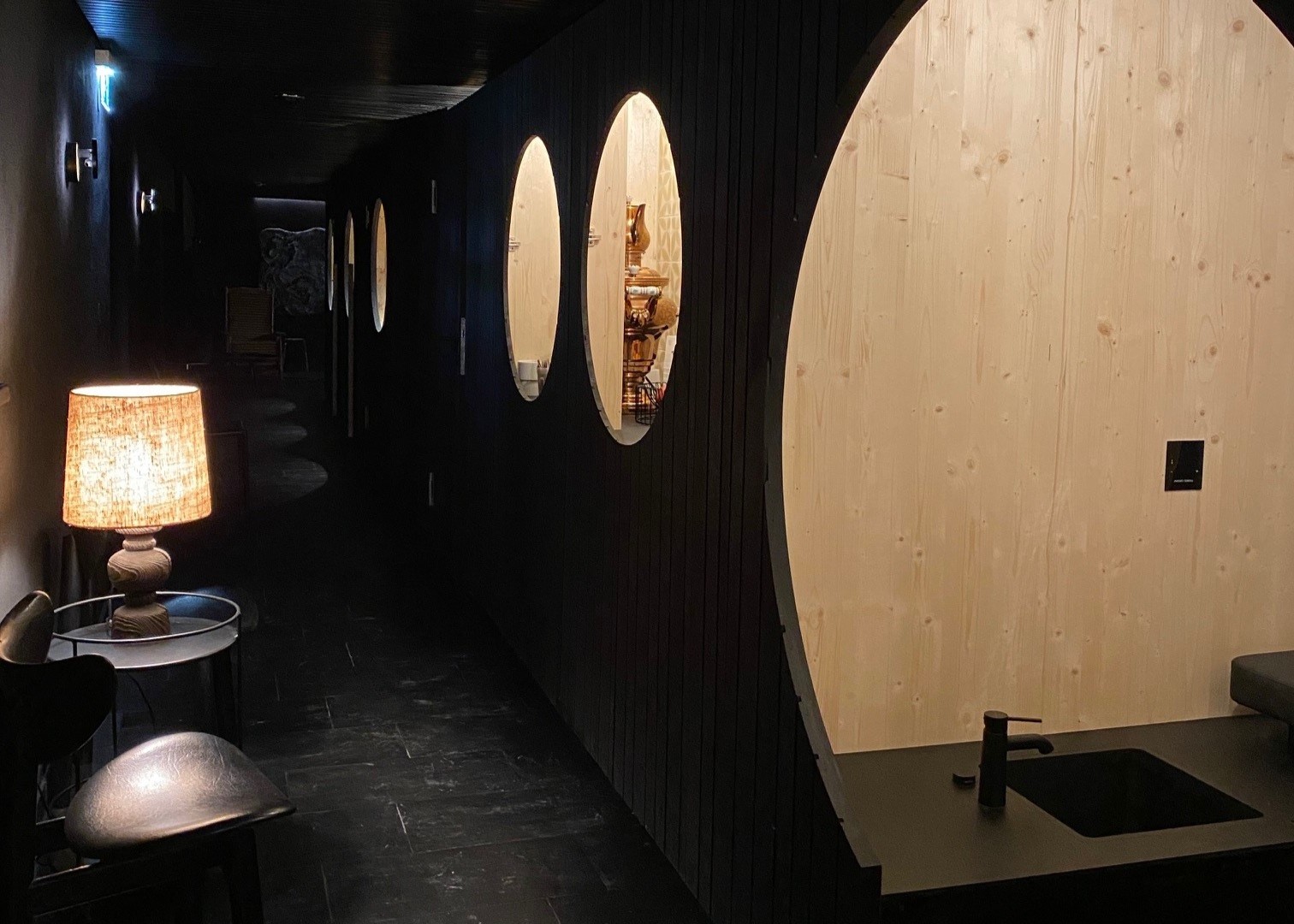 Dimly lit hallway with round window cutouts and pinewood accents in the SPA area of Ski-Hotel Mondschein in Stuben am Arlberg