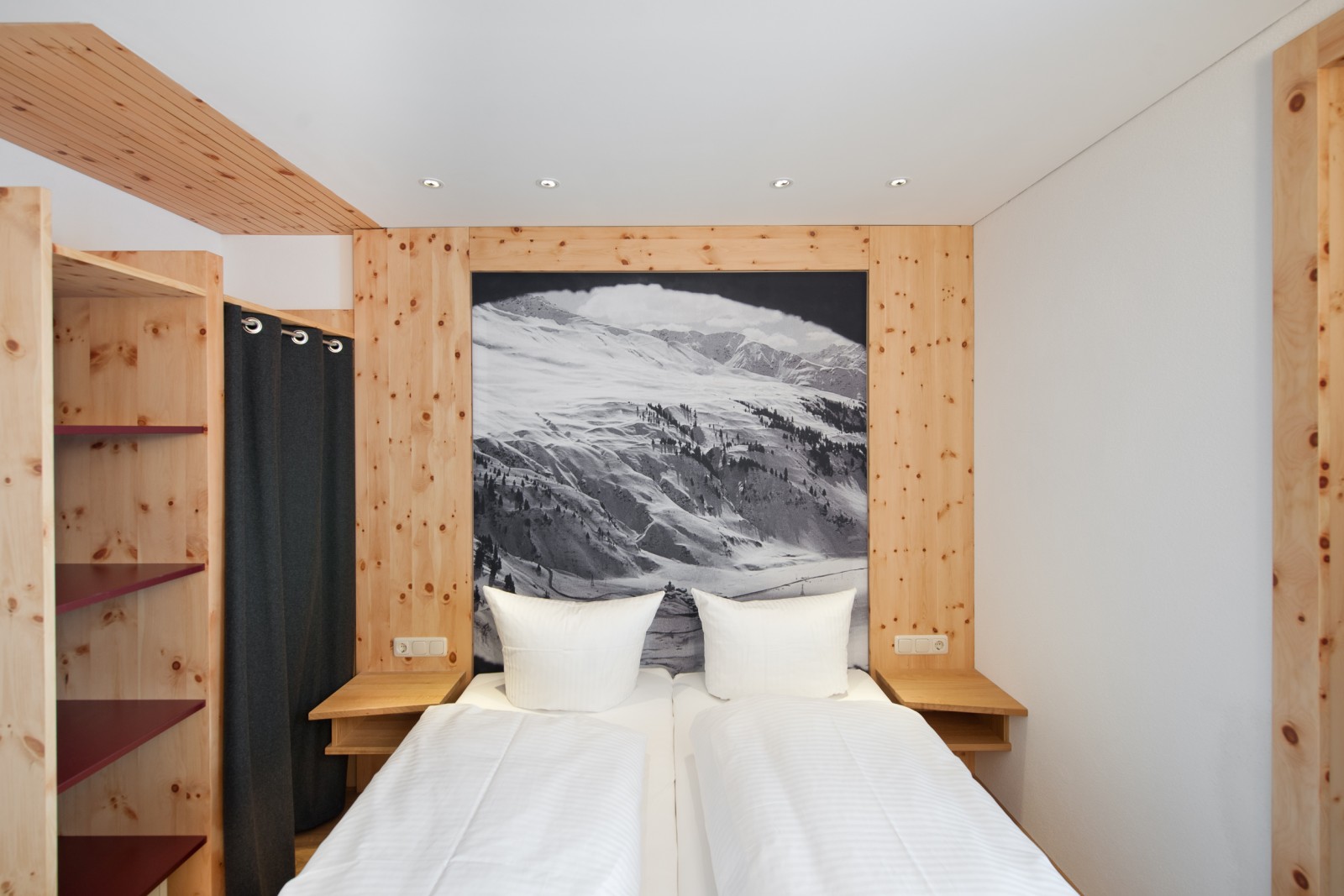 Queen-size bed in the Smart Double Room at Ski-Hotel Mondschein in Stuben am Arlberg, Austria – framed with local pine wood, alpine-modern design, and a black-and-white mountain landscape above the headboard