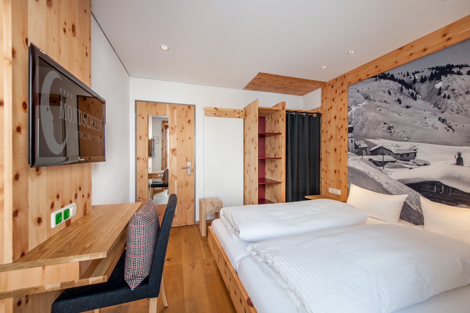 Smart Double Room at Ski-Hotel Mondschein in Stuben am Arlberg, Austria – featuring a queen-size bed, pine wood furnishings, a vintage alpine wall mural, work desk, and flat-screen TV