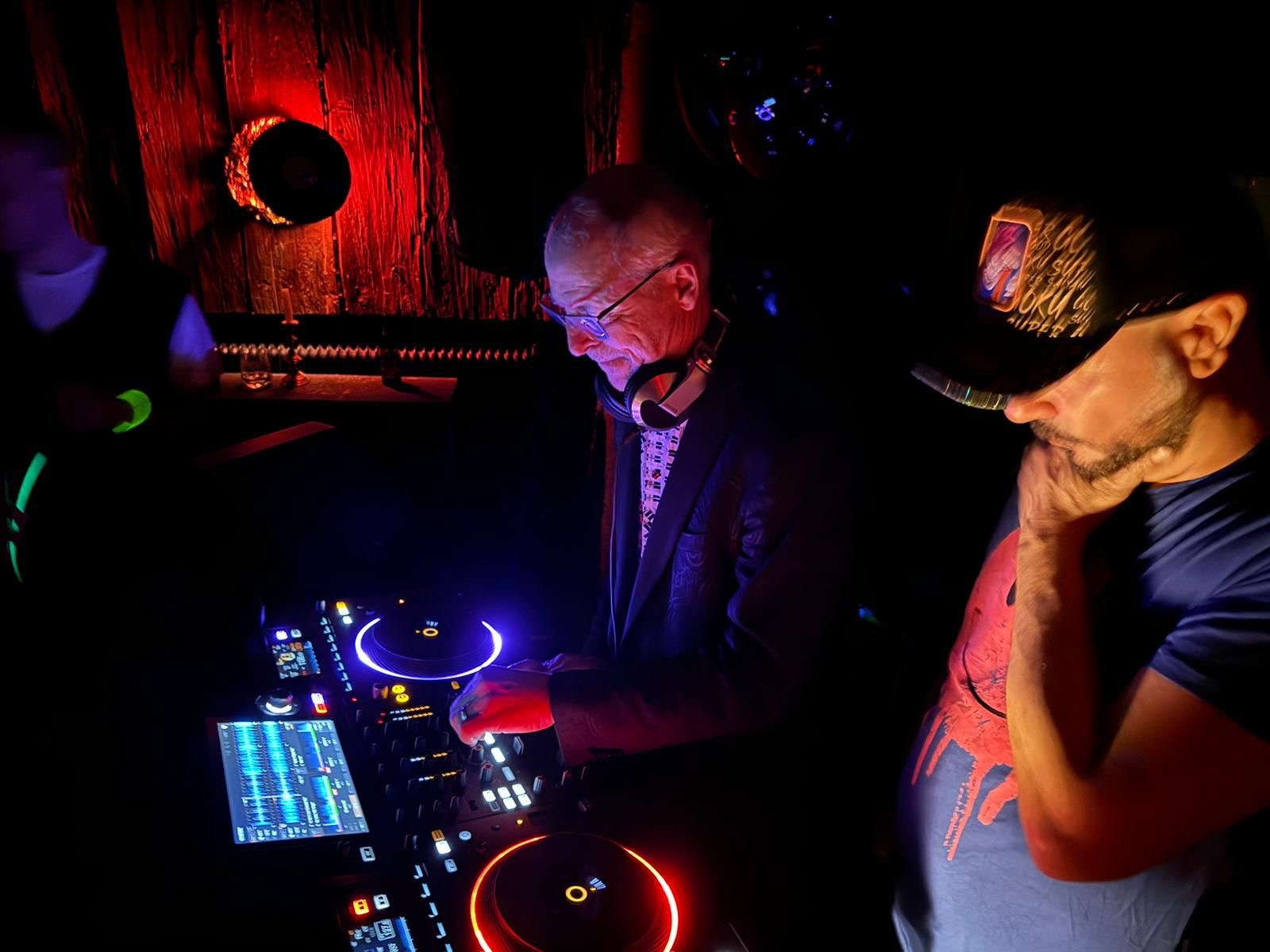 DJ Audiomed and Bedrud spinning tracks at a vibrant DJ night in the Mondschein Club, illuminated by neon lights and club ambiance
