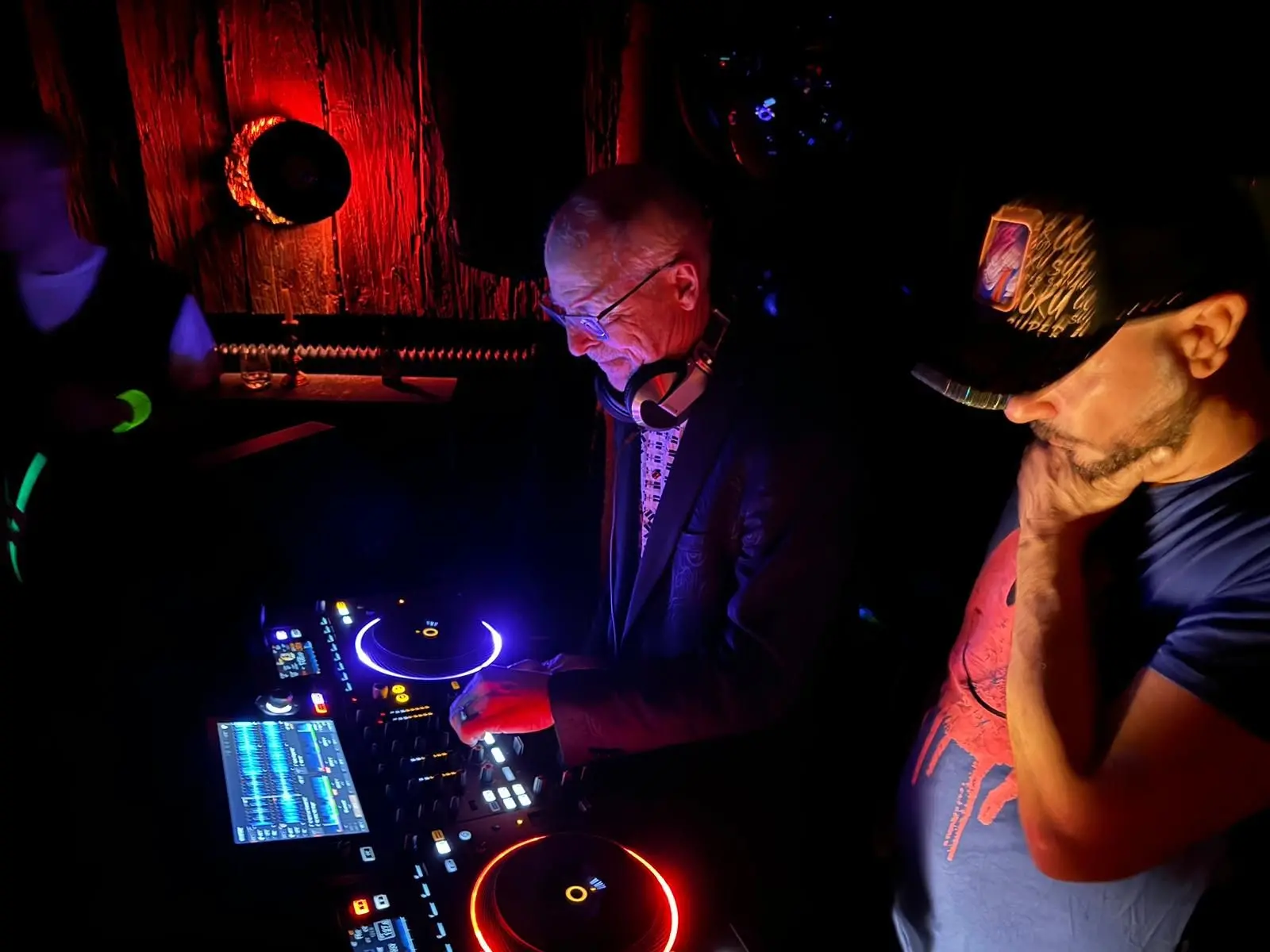 DJ Audiomed and Bedrud spinning tracks at a vibrant DJ night in the Mondschein Club, illuminated by neon lights and club ambiance