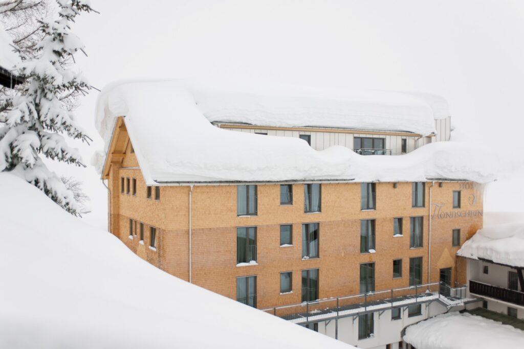 Ski-Hotel Mondschein in Stuben am Arlberg covered in deep snow, showcasing sustainable wooden façade after best-practice renovation