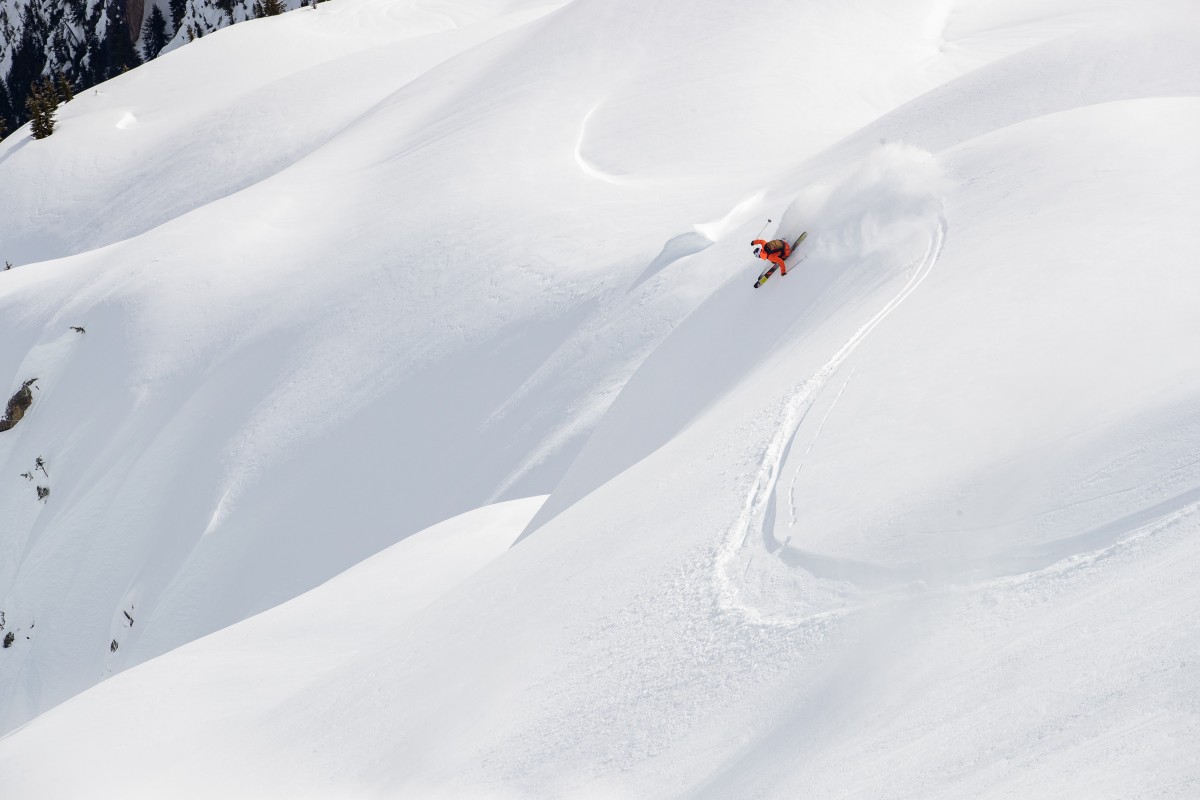 Skier Simon Hillis performing a deep powder turn on steep untouched backcountry terrain – photo by K2