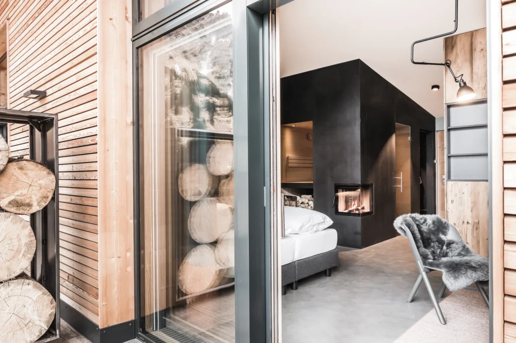 Discover modern alpine luxury at Chalet Mondschein in Stuben am Arlberg: private suite with open fireplace, in-room sauna, natural wood design and panoramic mountain views – perfect for relaxing summer or winter escapes.