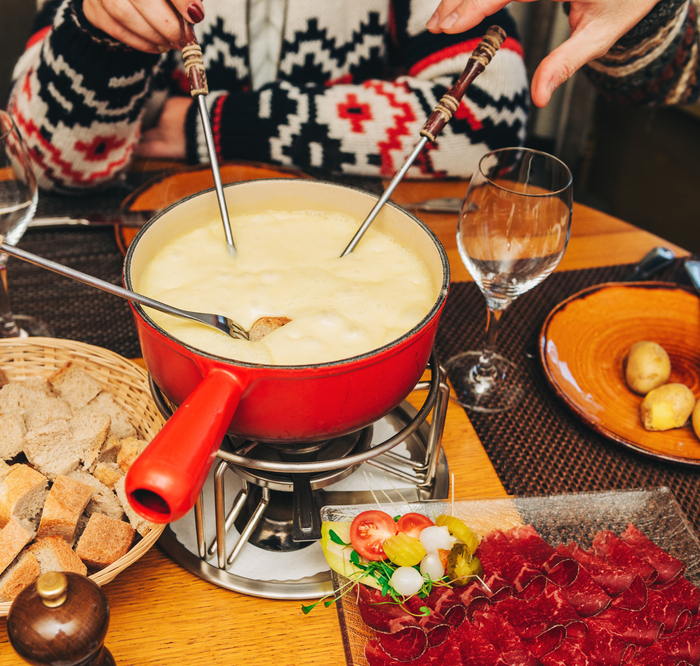 Friends,eating,cheese,fondue,in,a,cozy,traditional,swiss,restaurant